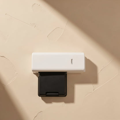 Slotread – Top view of a white USB card reader with a black SD card tray slid out, on textured beige plaster
