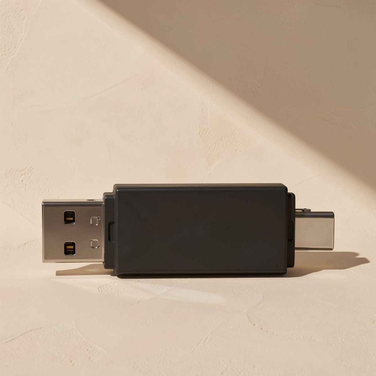 Readlink USB-C SD and TF card reader in black, USB-A and USB-C plugs visible, on a textured beige surface