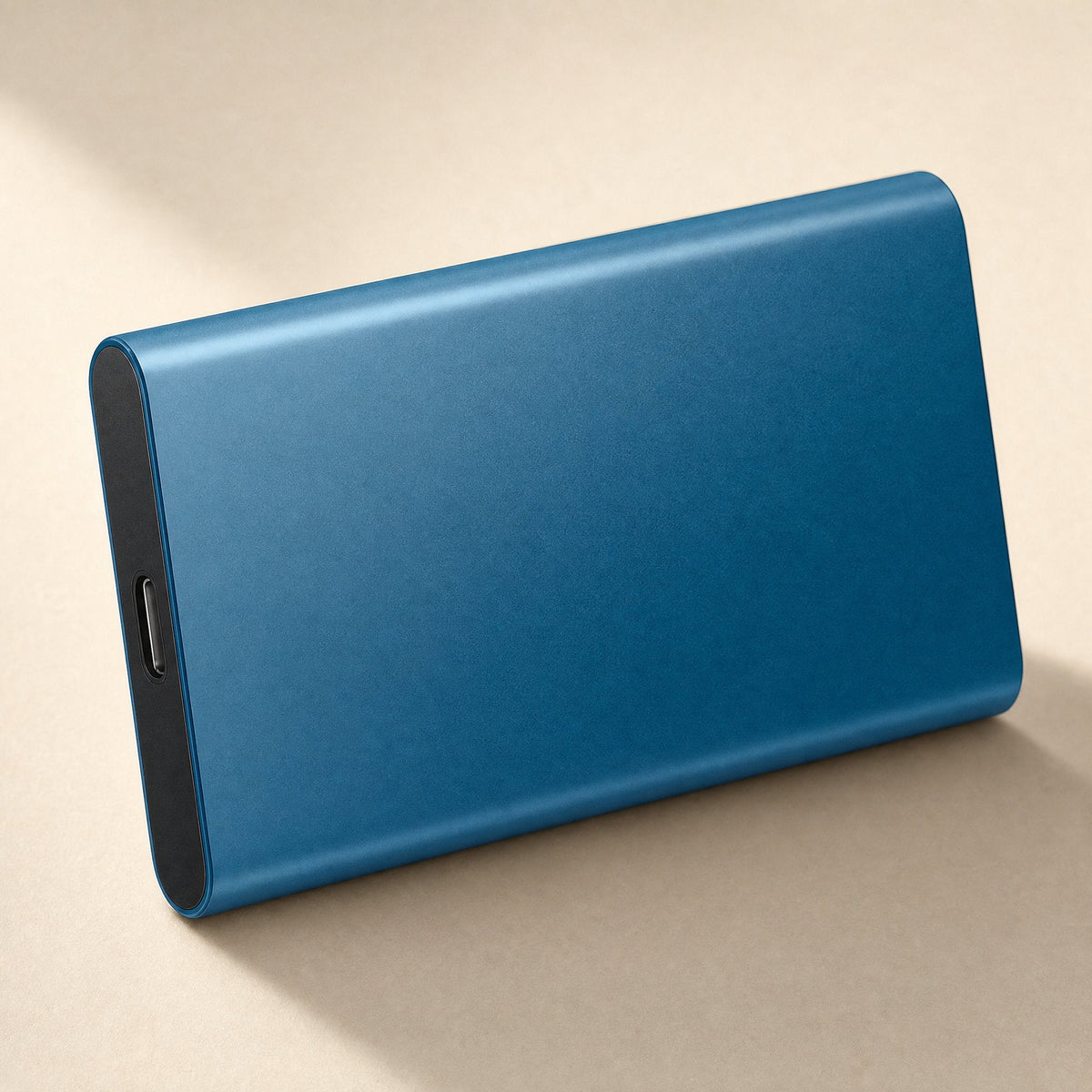 Datapocket – Blue metal portable SSD standing on its long edge, USB-C port visible on the end, on a beige surface