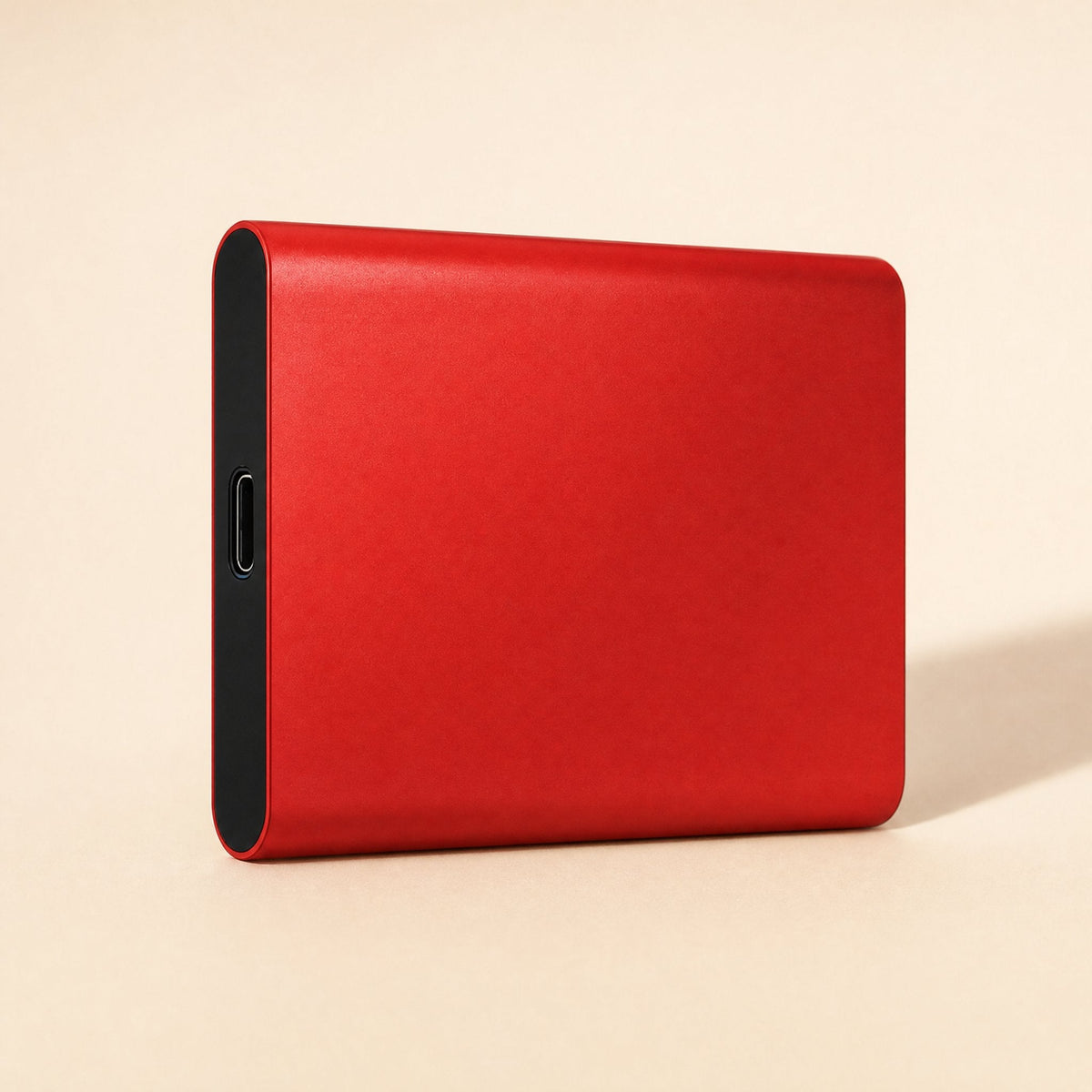 Datapocket – Red metal portable SSD at an angle showing its black end panel and USB-C port on a peach backdrop