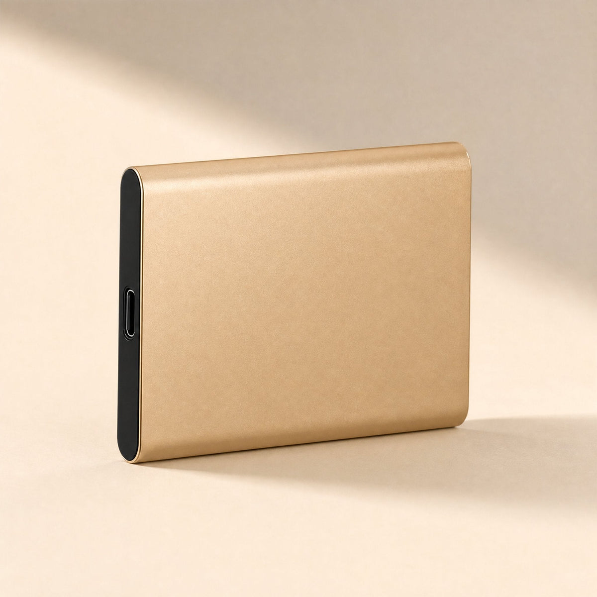 Datapocket – Gold portable SSD standing on its edge, brushed metal shell and USB-C port visible, in soft shadow