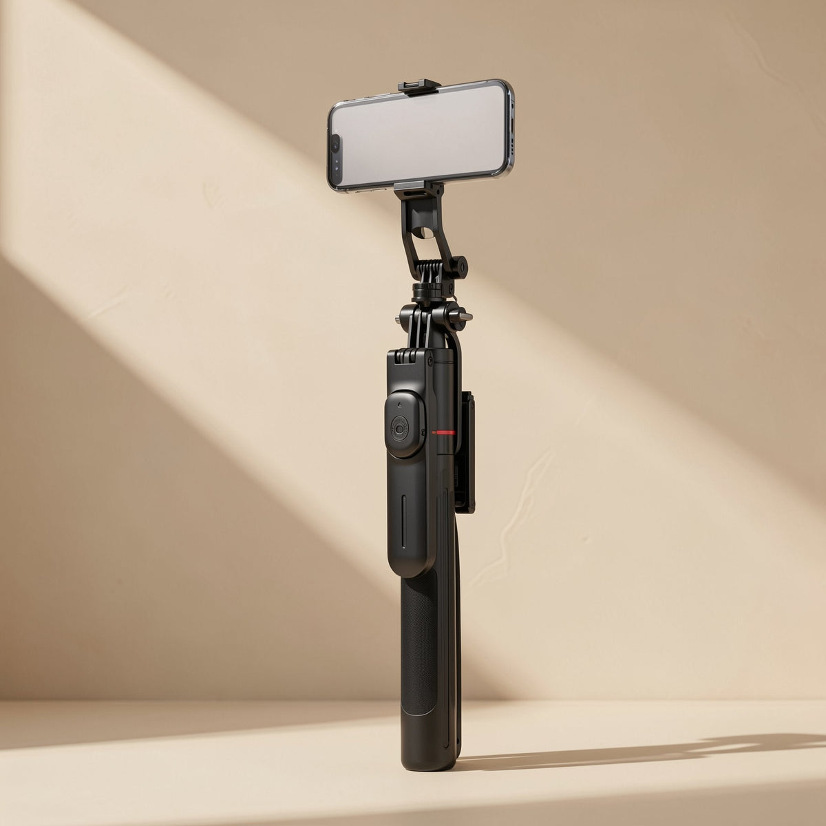 Snapframe Stainless Steel Bluetooth Selfie Stick holding a phone upright against a beige wall in angled light