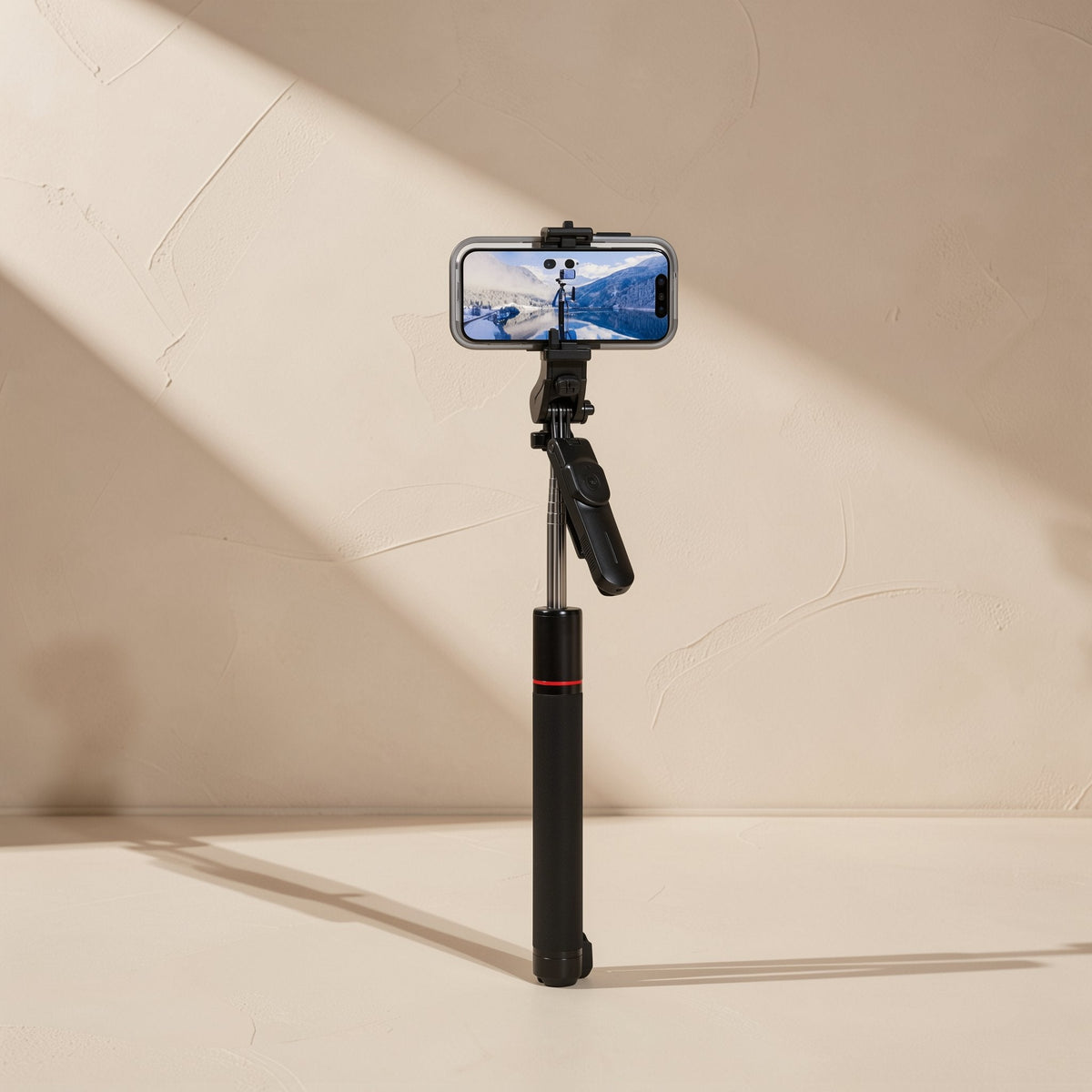 Snapframe – Selfie stick extended with a phone mounted on top, showing a landscape photo on screen, red ring on the black