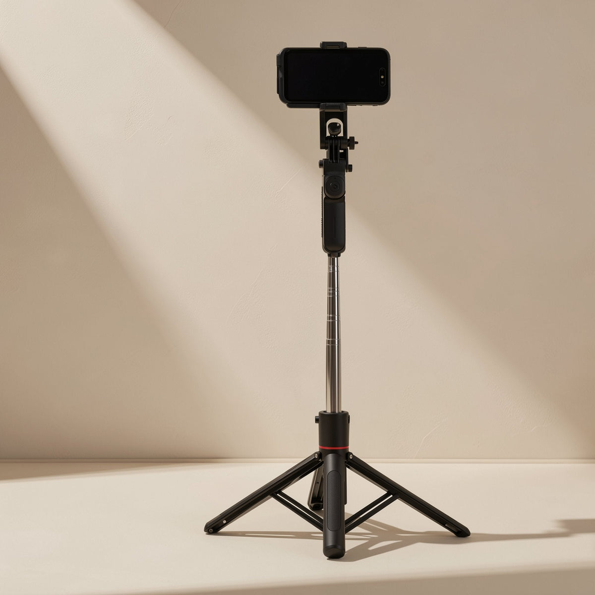 Snapframe – Selfie stick extended on its folded-out black tripod legs with a phone mounted on top, red ring at the base