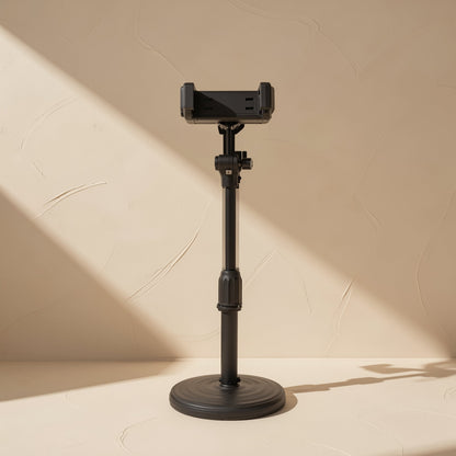 Tiltperch – Black telescopic desktop phone stand with an empty clamp, extended on a round base against a beige wall