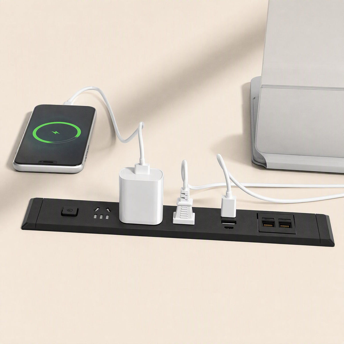 Desknest – Black socket on a desk charging a phone, with a power adapter, a plug in use and two network ports beside it