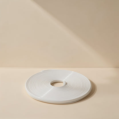 Neonflex – Unlit white neon light strip wound into a flat disc, shown with its end tucked in on a cream background