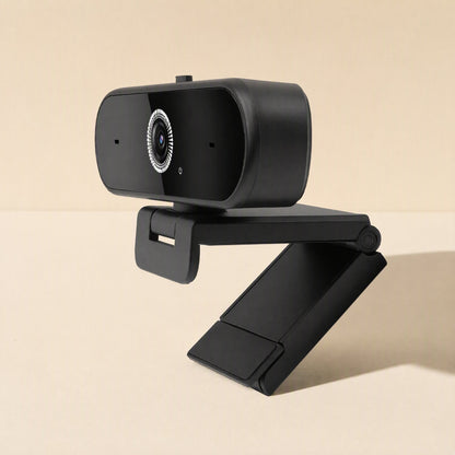 Talkframe – Side-angled view of the black webcam on its open folding clip arm, casting a soft shadow on beige