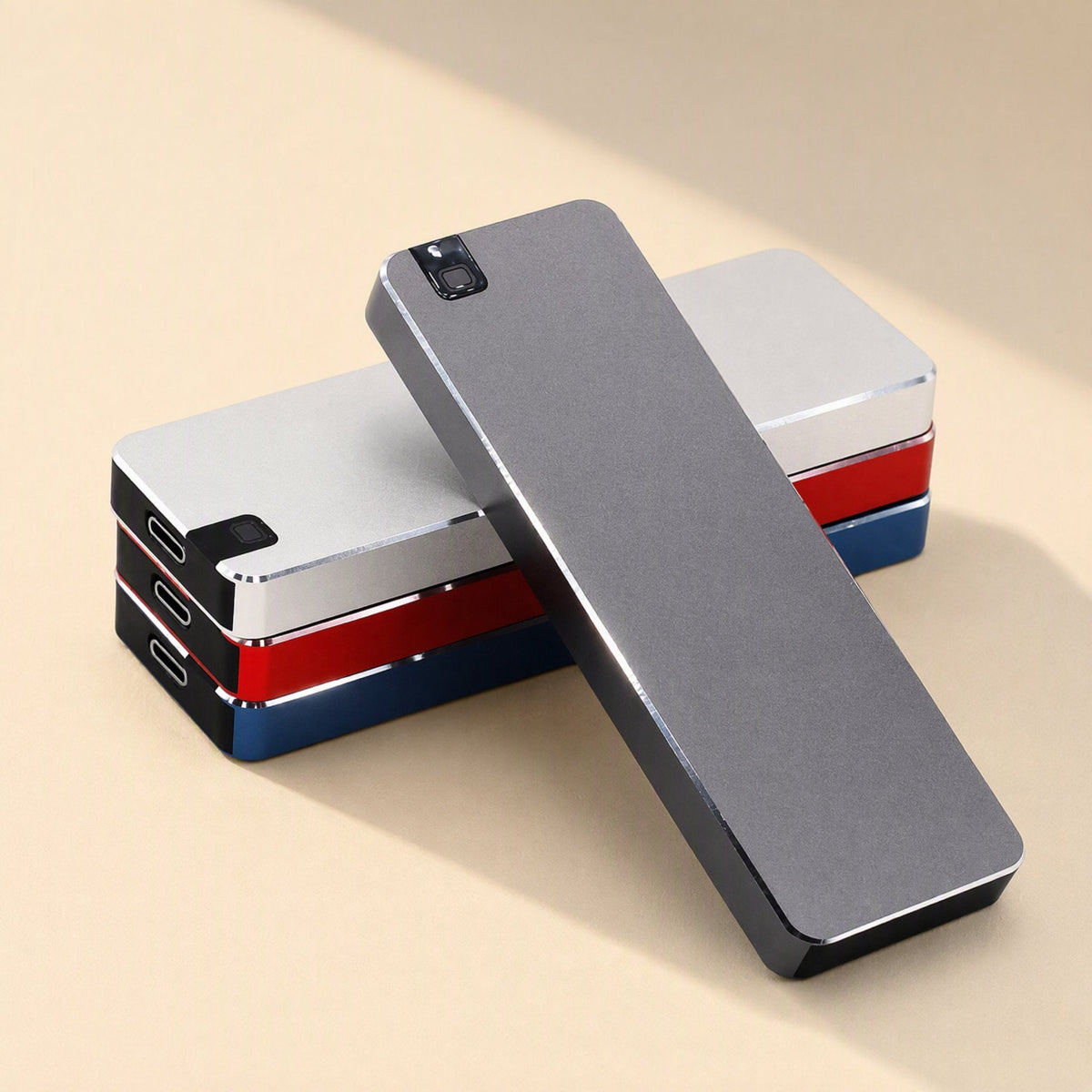 Steeldrive Metal Shell External Solid State Drive in gray leaning on stacked silver, red and blue drives