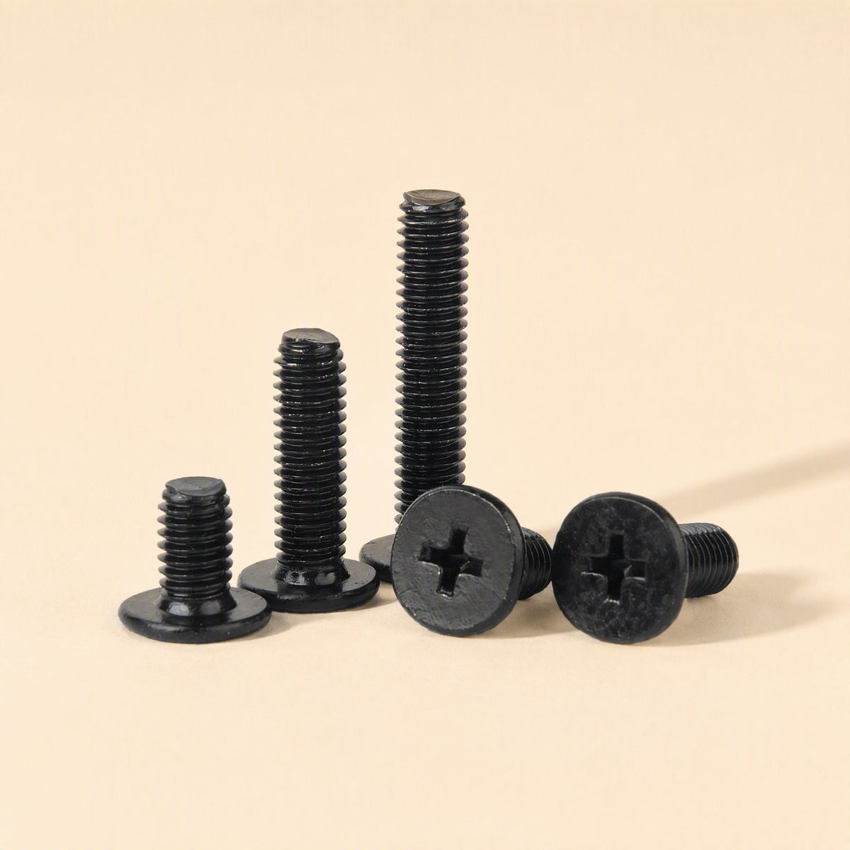 Flatfix Laptop Screw Kit – three black screws standing upright beside two lying flat showing their cross-shaped drive heads