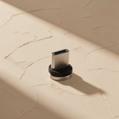 Magtrio – Detached USB-C magnetic tip with a black base and silver rim standing on a textured cream surface