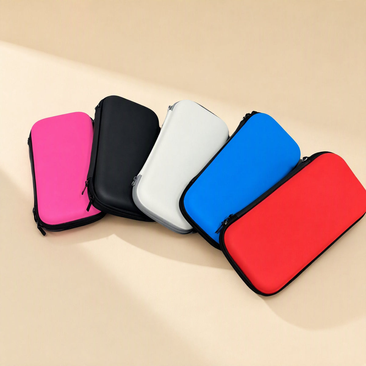 Switchstow PU Switch OLED storage bag in pink, black, white, blue and red, arranged on a beige background