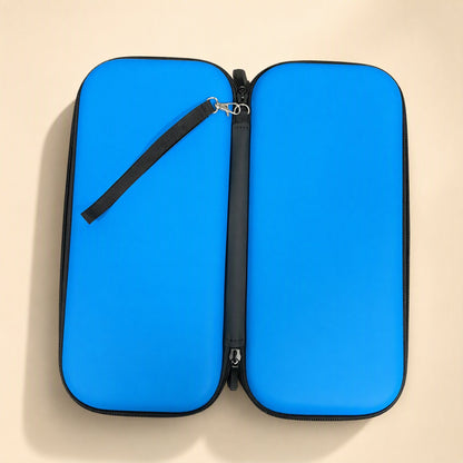 Switchstow – Blue zippered case laid open flat, showing the black wrist strap and zipper pull on a beige surface