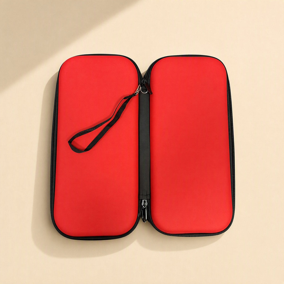 Switchstow – Red hard shell bag opened flat from above with a black wrist strap clipped to the zipper edge