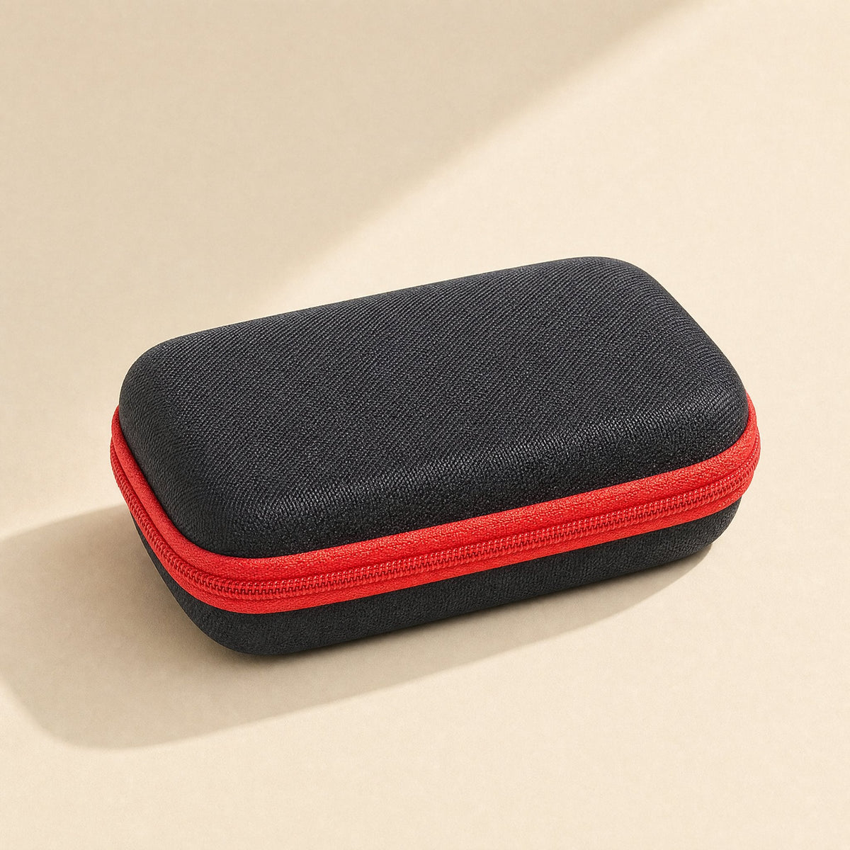 Padpouch – Closed black hard EVA case with red zipper, seen from a three-quarter angle on a cream background