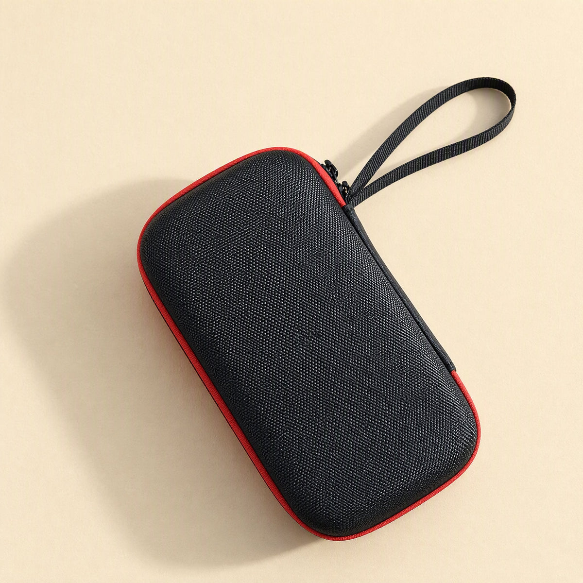 Padpouch – Top view of the black textured case with red edging and a black wrist strap at the zipper end