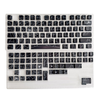 Loomwire – Black spider web keycaps laid out in clear plastic trays, showing the full 130-key set unmounted