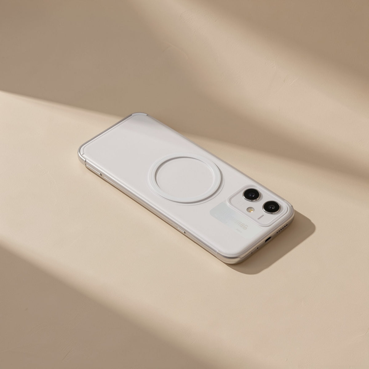 Cushgrip – White phone with a circular magnetic ring on the back lying on a cream surface in soft light