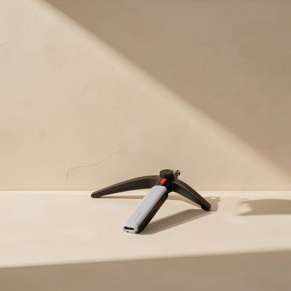 Portlink – Slim silver and black hub standing upright on a small black tripod stand against a beige wall