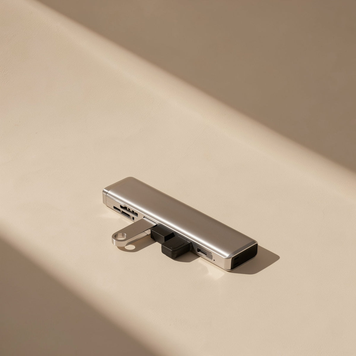 Portlink – Silver hub lying on a beige surface with a USB flash drive plugged into its side port