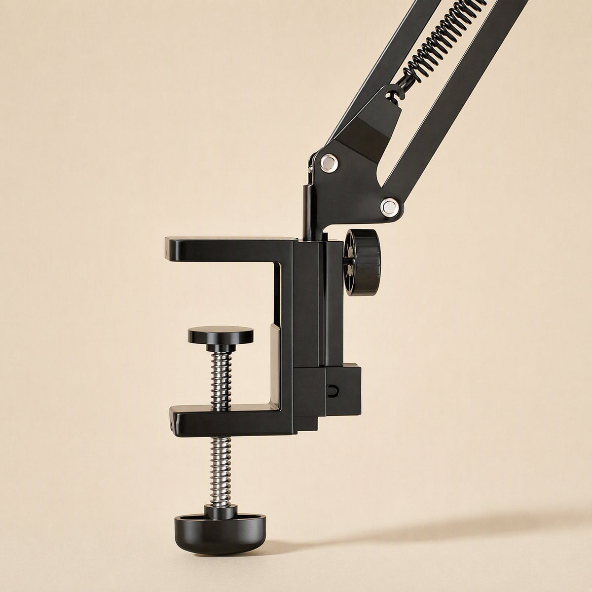Metalhold – Close-up of the black C-clamp base with a knurled thumb screw and spring detail on the desk arm