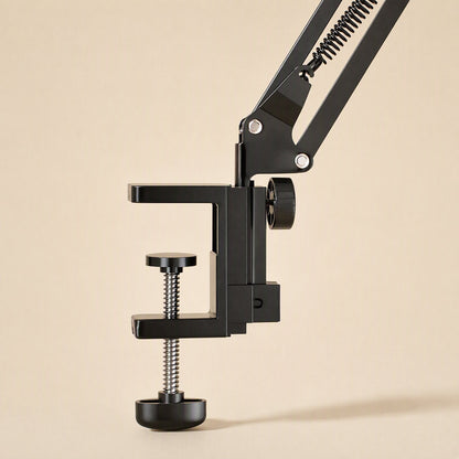 Metalhold – Close-up of the black C-clamp base with a knurled thumb screw and spring detail on the desk arm