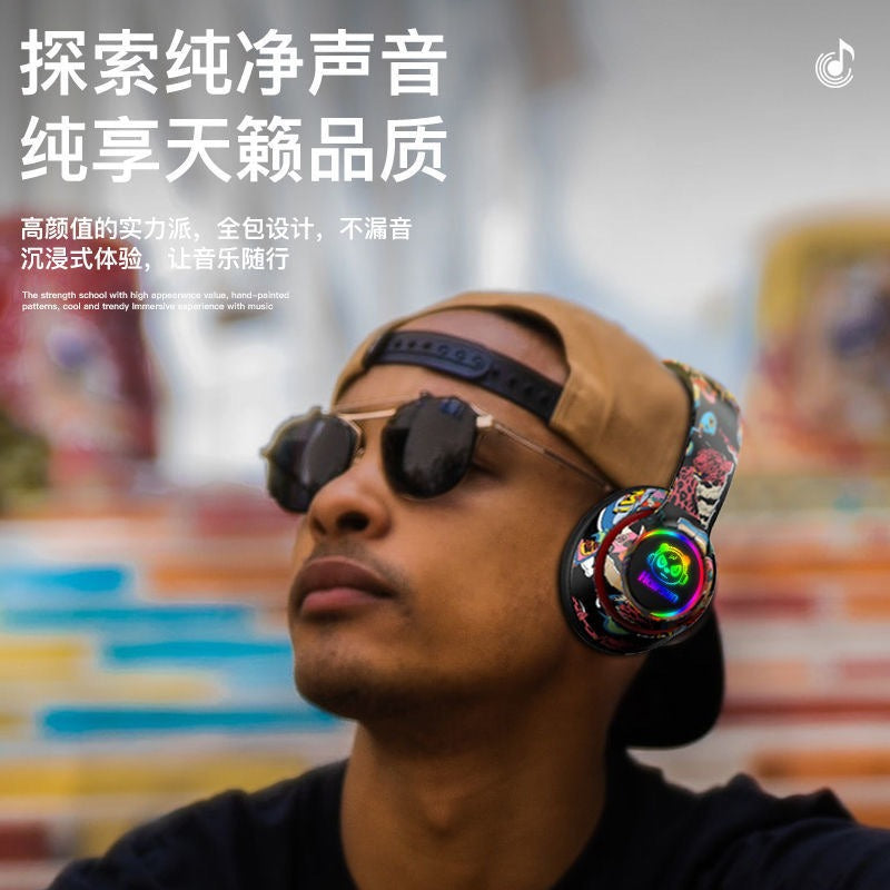 Rovex – Man in sunglasses and tan cap wearing the graffiti headset with lit ear cup, outdoors against colourful wall