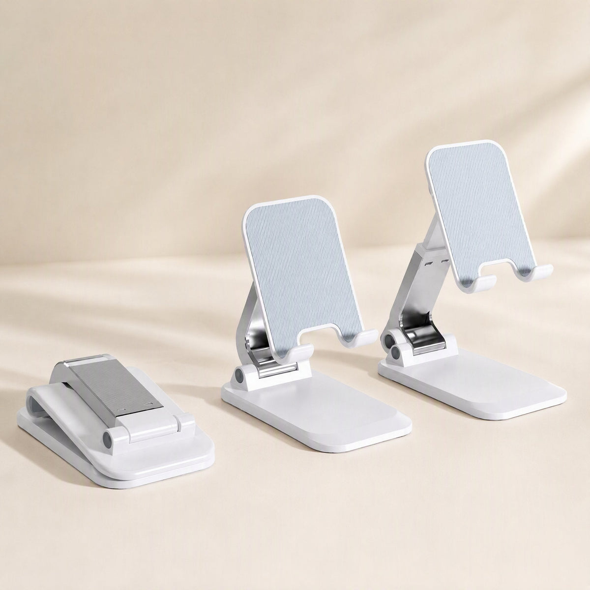 Foldcradle ABS Foldable Phone Stand in white, shown folded flat beside two stands at different heights