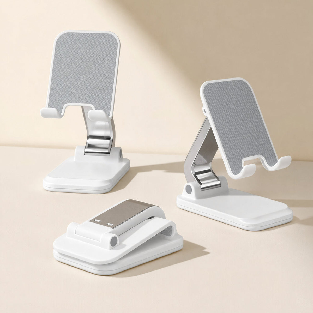 Foldcradle – Three white foldable stands on a beige surface: two raised with gray grip pads, one folded flat