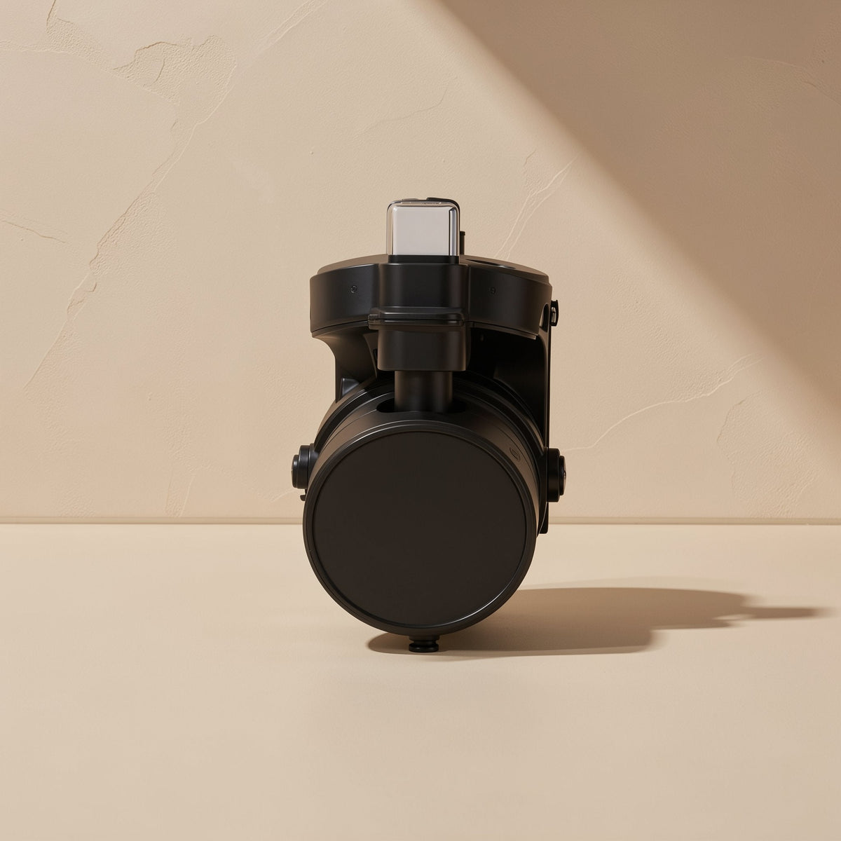 Spinloop cable organizer in black, front view with a USB-C connector on top, against a beige wall