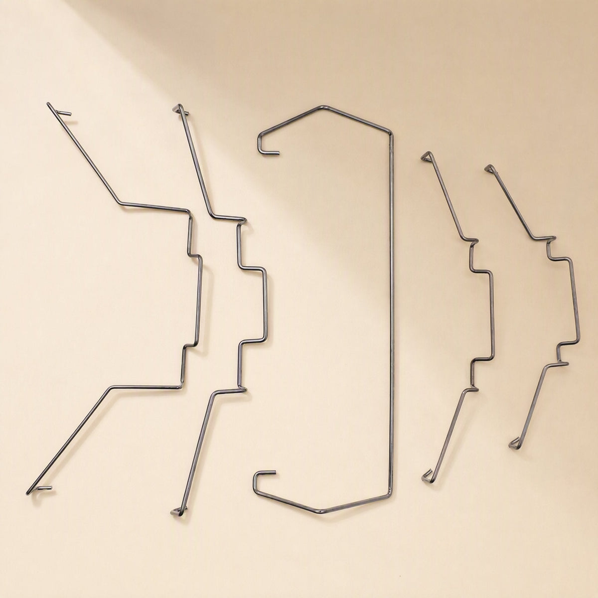 Fanlatch – Five steel wire fan clips in varied shapes arranged in a row on a cream surface, angled view