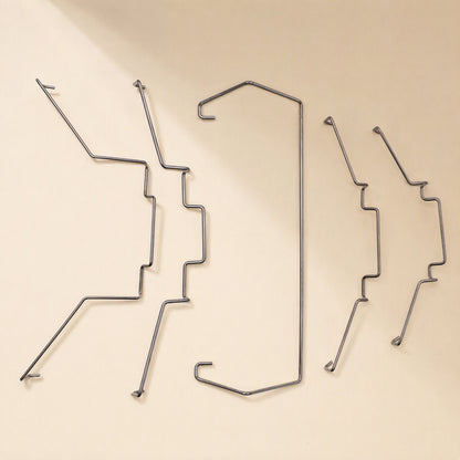 Fanlatch – Five steel wire fan clips in varied shapes arranged in a row on a cream surface, angled view