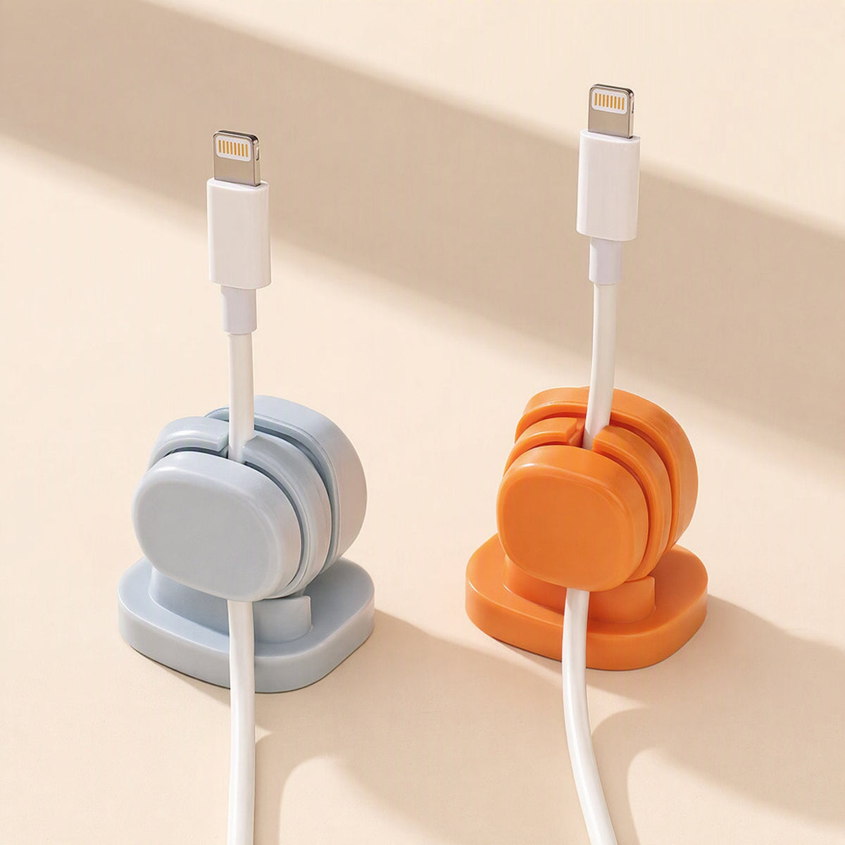 Spincoil – Two clips in blue and orange standing on a surface, each holding a white Lightning cable upright
