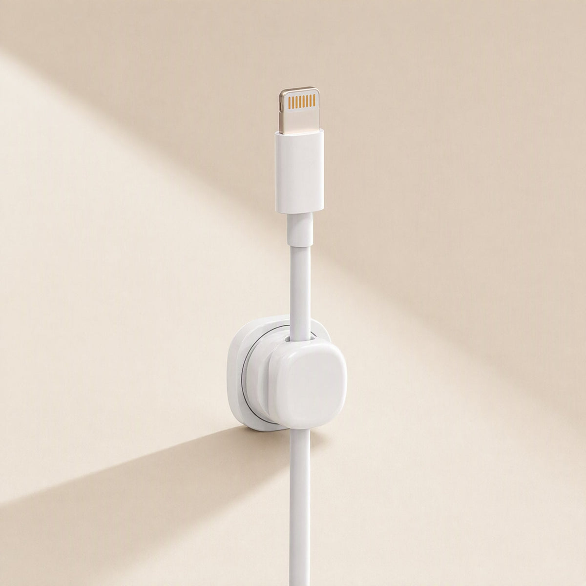 Spincoil – White clip on a wall holding a white Lightning cable in place against a beige background