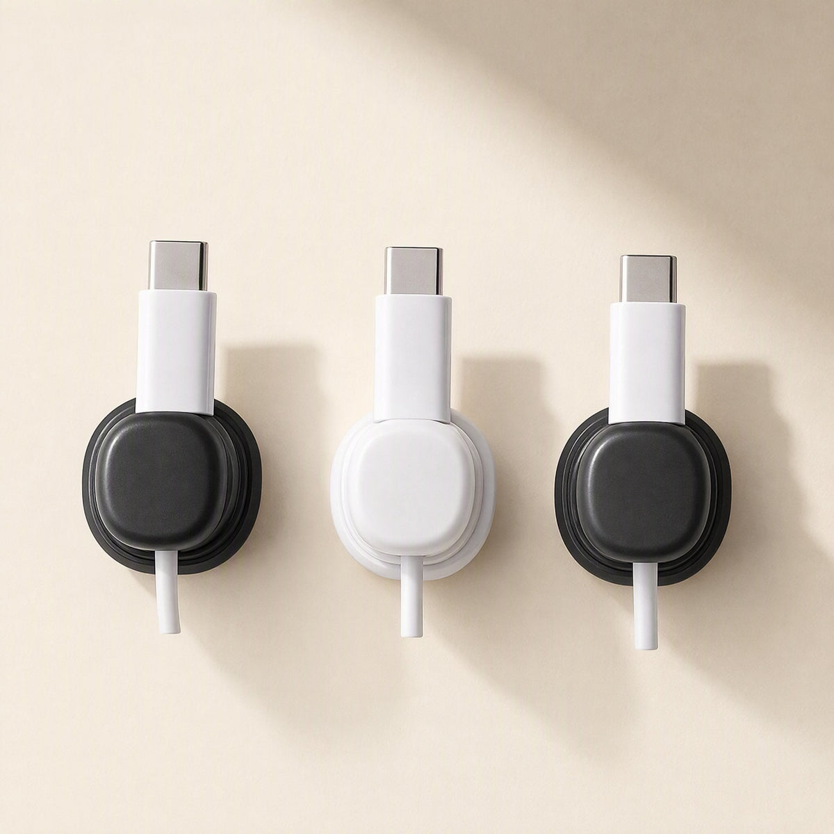 Spincoil – Three wall-mounted clips in black, white and black, each holding a white USB-C cable