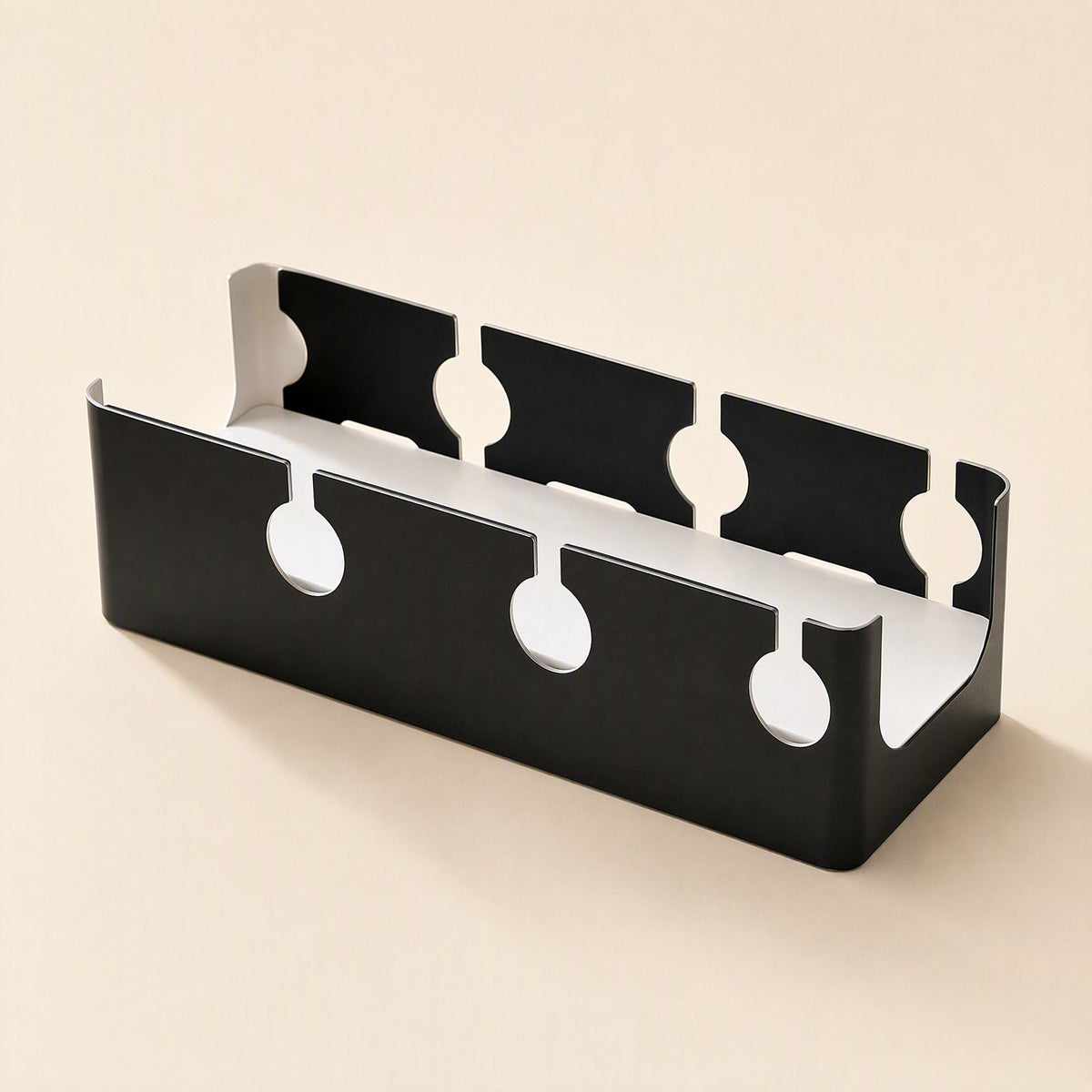 Deskspan – Black steel cable tray with keyhole-shaped cutouts along its front and back walls, shown without clamps
