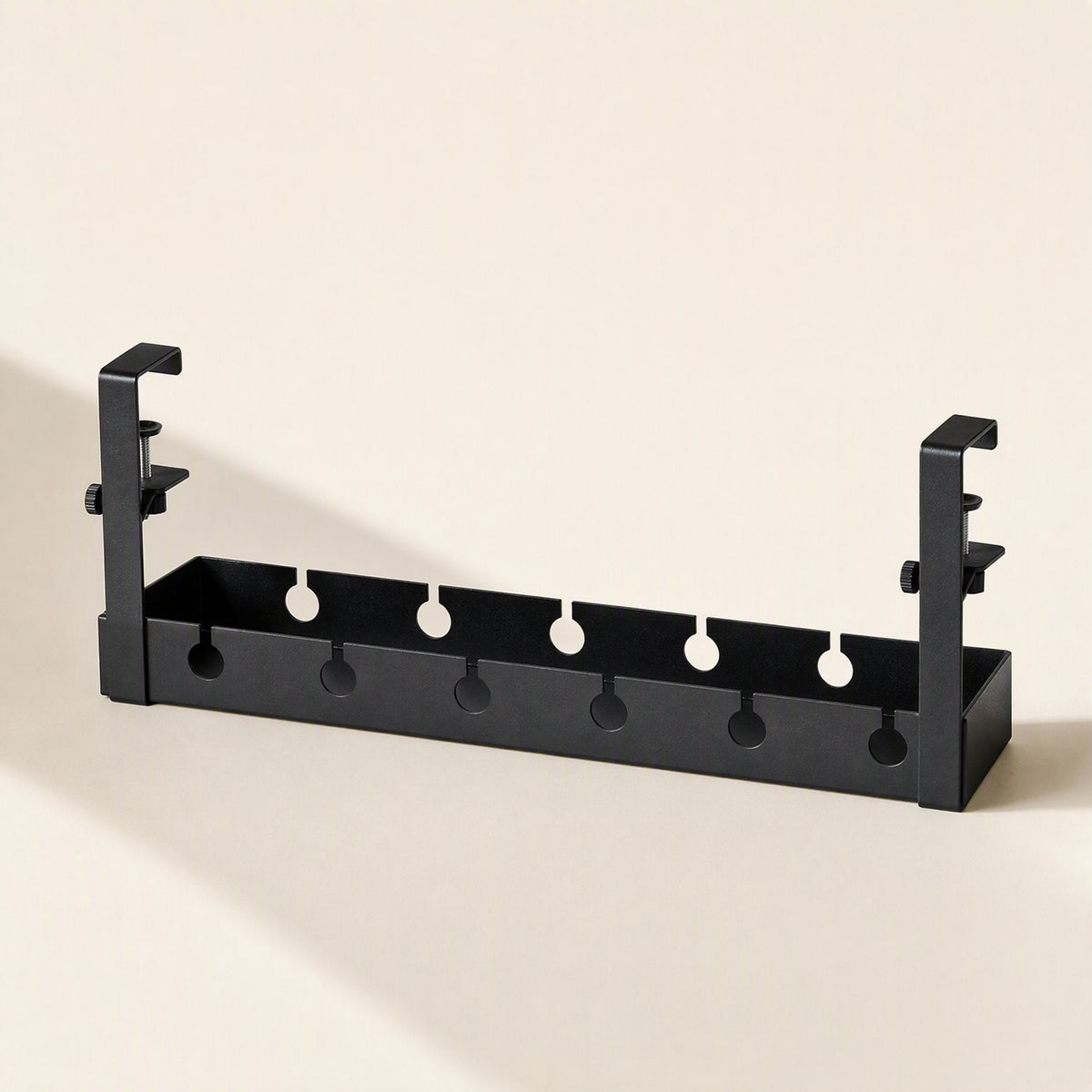 Deskspan – Front view of the black rack with six round cutouts along the front and two upright clamp brackets
