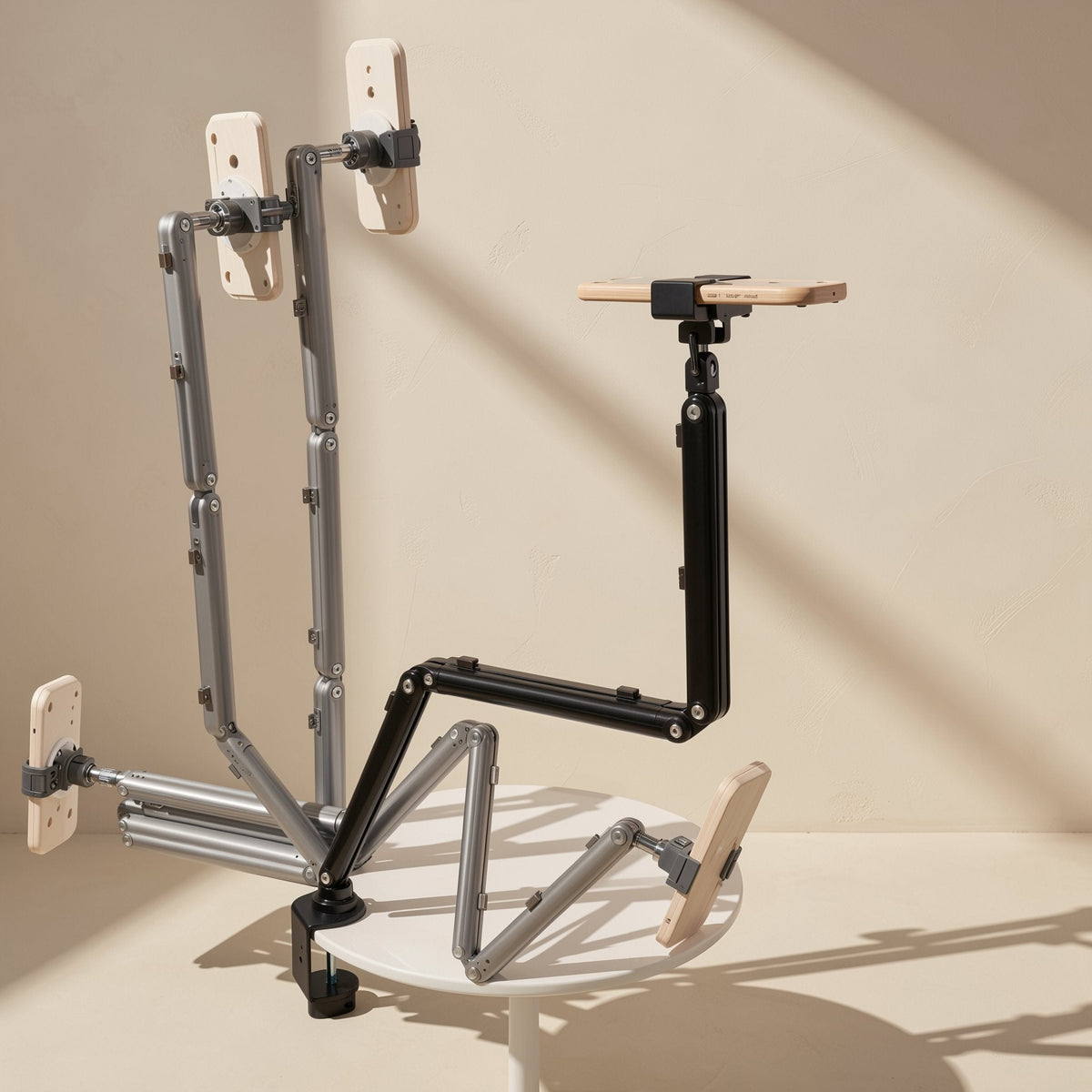 Foldvoice – Foldable arms in grey and black in several poses holding wooden phone-shaped mounts, clamped to a round table