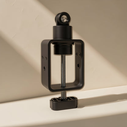 Foldvoice – Close-up of the black desk clamp base with threaded screw and swivel joint against a beige wall
