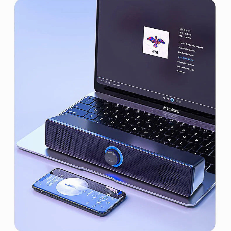 Humline – Black soundbar speaker with blue-lit knob in front of a MacBook, with a smartphone beside it on the desk