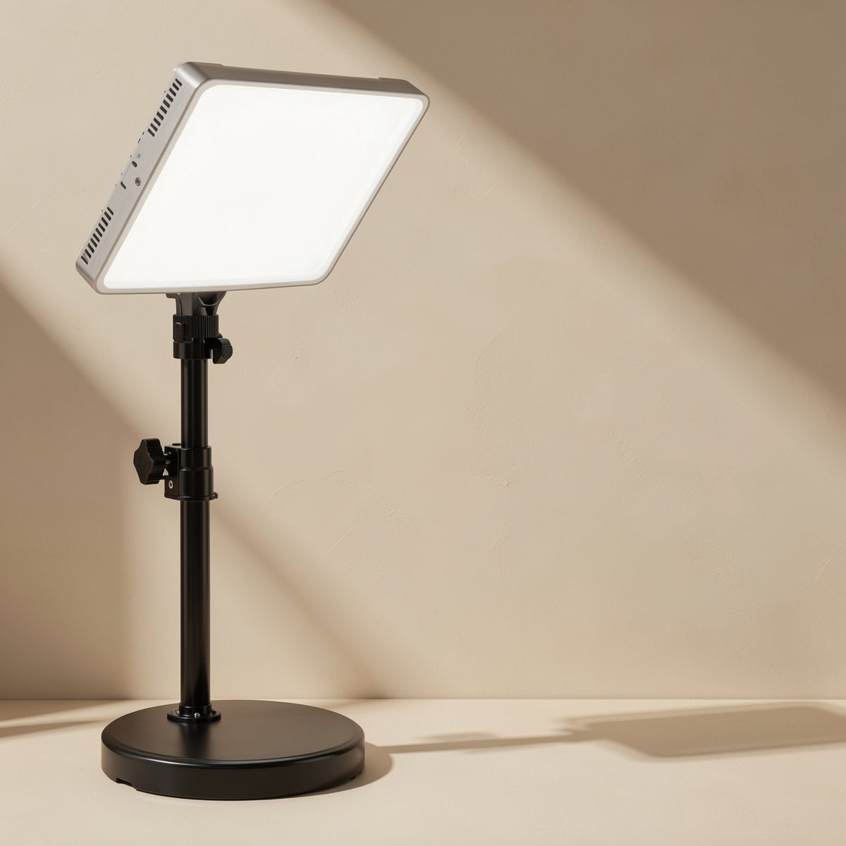 Facegleam – Silver-edged LED panel tilted on a black telescoping stand with a round weighted base