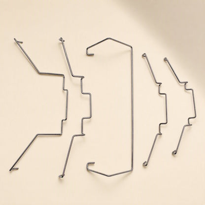 Fanclip – Five bent steel wire fan clips in two sizes arranged in a row on a beige surface, angled view
