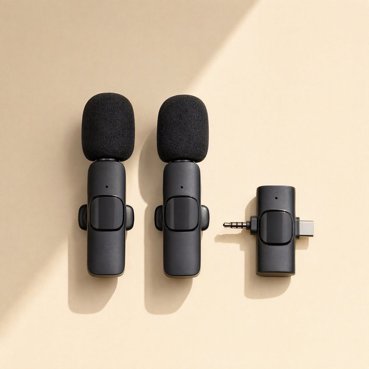 Voiceclip – Two black foam-topped clip mics beside a compact USB-C receiver with 3.5mm plug on a cream background