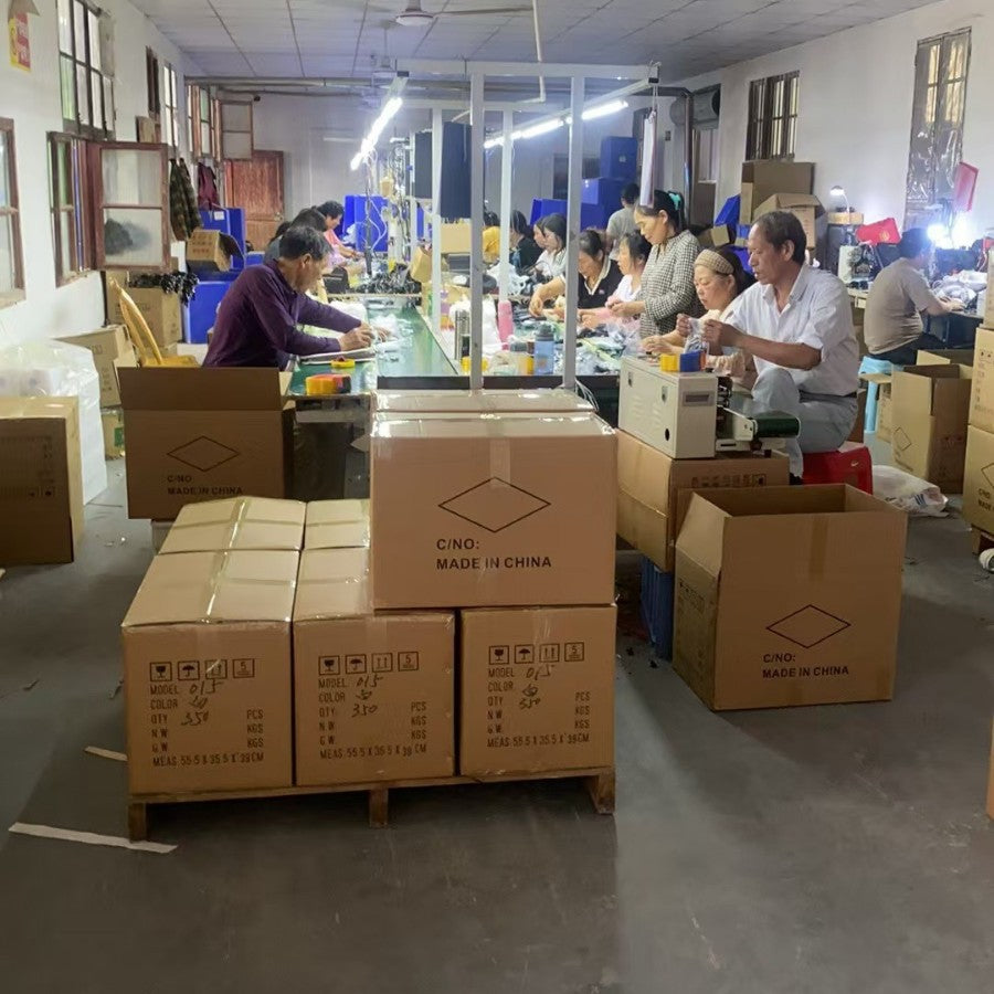 Clicken – Workers assembling and packing mice at long tables in a factory, with cartons marked Made in China in front