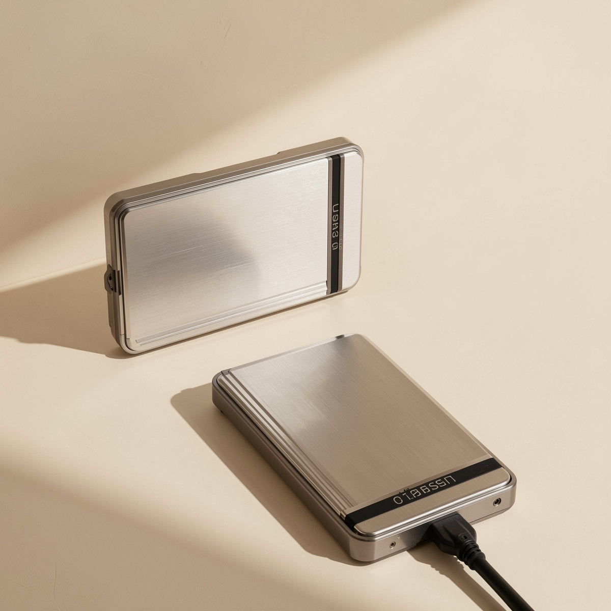 Datahush – Two silver enclosures, one lying flat with a black USB cable plugged in and one propped up behind