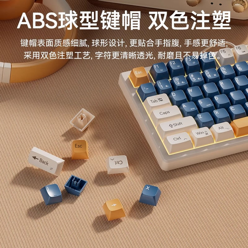 Keystrike – Close-up of blue, white and orange keycaps, with several loose caps and a switch beside the keyboard