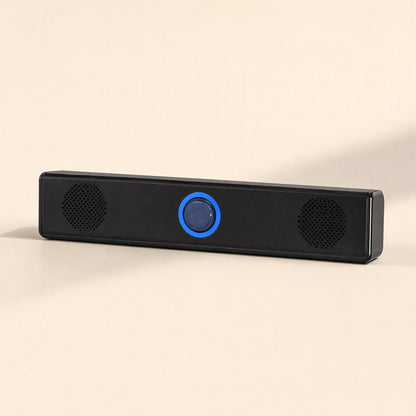 Soundbit – Black mini soundbar with a lit blue ring knob and two round speaker grilles, front view on a beige surface