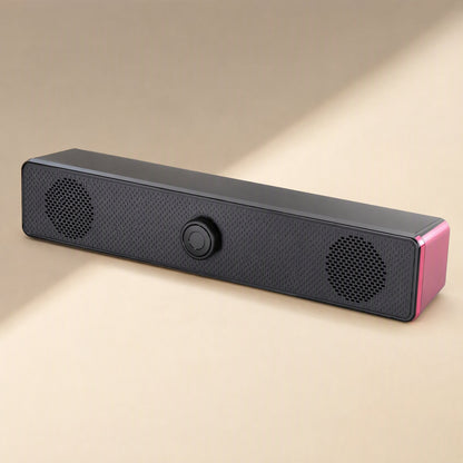 Soundbit – Black soundbar speaker with pink side panel and an unlit center knob, angled on a cream background