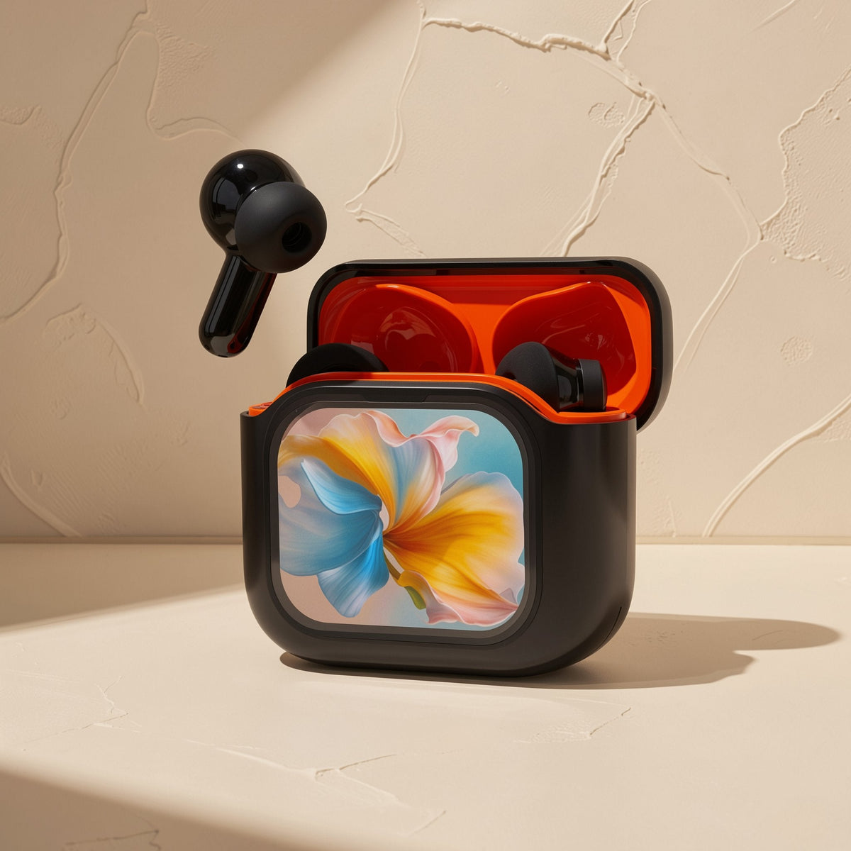 Quietwave – Open black case with orange interior and floral front panel, one earbud floating above, on a beige surface