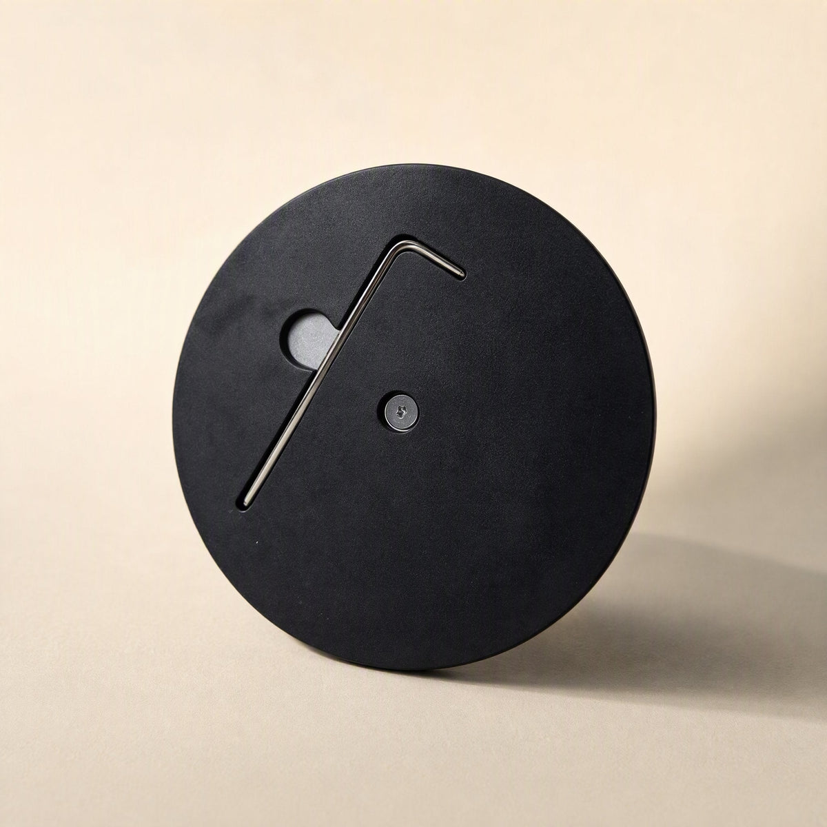 Swiveldesk – Underside of the round black base with an allen key stored in a recessed slot and a bottom screw